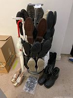 Shoe tree holding multiple pairs of ladies shoes in various styles, colors and sizes 6.5 to 8. Additional black boots and umbrella visible nearby.