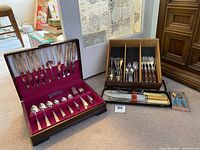 Overview photo showing all the items including WA Rogers silverware set in box, serving utensils, wooden-handled cutlery, and vintage carving set with sharpening steel.