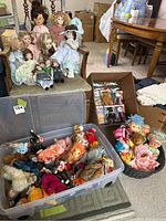 Overall view of the dolls seated on a chair and the bins with Ty Beanie Babies and dolls in knitted clothing
