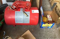 MotoMaster red air tank with coiled red air hose inside a garage.