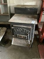Full view of the antique cast iron wood stove showing its solid rectangular shape and embossed front door.