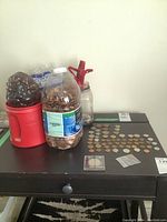 Wide view of three containers holding mixed Canadian pennies along with coins spread on table surface.