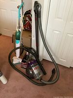 Overview showing Dyson canister vacuum with hose, extension wand, attachments and SteamTek floor steamer