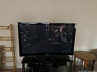 Front view of LG plasma TV on stand with visible remote on the shelf below.