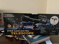 Front of the box displaying the National Geographic branding, an image of the telescope, and the product name '375X Land and Sky TELESCOPE' along with some celestial object images.