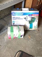 Photo of boxed Mastercraft impact wrench kit and Jobmate detail sander box with green tape.