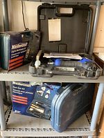 Mastercraft digital multimeter and heat gun kits in storage on shelf, showing case details and tool grips.