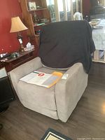 Front three-quarter view of chair with throw over back, remote and manual on seat