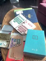 Overall view of table with stamp albums, cigarette boxes and loose envelopes with stamps.