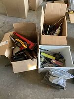 Three containers holding assorted tools including pipe wrenches, pliers, measuring tape and screwdrivers
