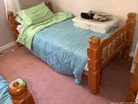 Full side view of the assembled solid pine twin four-post bed frame with bedding arranged on it.