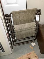 Folded zero gravity chair showing fabric and metal frame in basement corner.