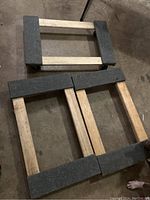 Photo showing three wooden furniture dollies with gray carpet pads placed on a concrete floor.