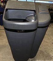 Front and side angled view of the gray A.O. Smith water softener unit showing the top openings and branding.
