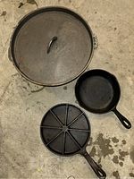 Photo of the cast iron pot with lid, small skillet, and segmented pan arranged on floor