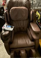 Front view of brown Cozzia massage chair showing headrest, armrests, seat cushion and foot massager