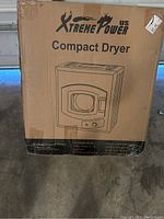 Photo of the sealed cardboard box showing the Xtreme Power Compact Dryer branding with front loading dryer illustration.