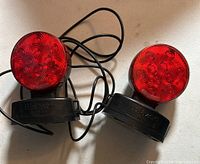 Pair of red LED trailer lights with wires, laying on a white surface.