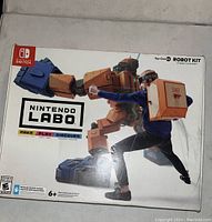 Front view of Nintendo Labo Robot Kit box featuring image of a person wearing cardboard robot suit with Nintendo Switch controllers.
