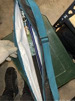 Green soft case partially unzipped showing multiple pool cue sections inside separated by protective sleeves.