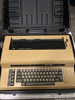 Overview of the beige Sears The Electronic Communicator 1 typewriter with integrated keyboard and function keys in carrying case.