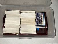 Top-down view of a large stack of various sports trading cards stored in a plastic bin.