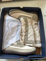 Pair of beige and cream colored women's winter boots with faux fur lining, quilted panel and side zipper, in original box with tissue paper.