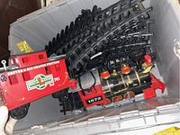 Locomotive and Denver & Rio Grande Western caboose with multiple curved track pieces inside a plastic storage bin.