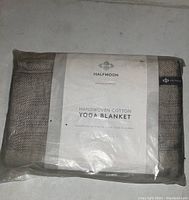 Packaged Halfmoon handwoven cotton yoga blanket showing label and fabric texture.