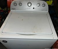 Front view of Whirlpool washing machine with control panel and closed lid showing some surface wear and stains.