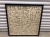 Front view of abstract paper shadowbox framed art showing intricate cutout lattice design in cream paper with black frame.