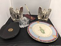 Photo of the lot showing eagle bookends, glass organizer, Cross pen with stand, black US Senate plate, and Tiffany Bicentennial plate