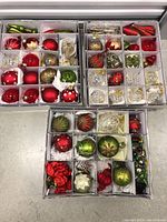 Three open compartment boxes filled with assorted glass ornaments and tinsel picks