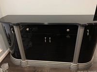 Front view of black lacquer buffet with central doors and silver ribbed accents.