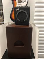 Rock Jam electric guitar with sunburst finish, black amplifier, and brown cajon subwoofer shown in clear front view.