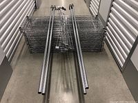 Stack of chrome wire shelves and long tubular posts laid in storage hallway