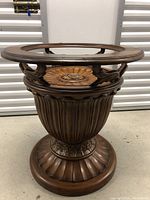 Full view of Tommy Bahama wooden table base showing circular open top and detailed carved wooden base with floral motifs.