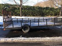Side view of entire trailer showing length, mesh sides and wooden ramp gate