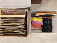 Top view of two storage bins, one with a collection of vinyl records in cardboard box, other with vinyl discs and 45 RPM records in paper sleeves.