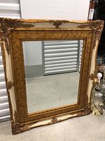 Full view of the rectangular beveled mirror with golden ornate frame.