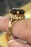 Close-up side angle showing the smokey quartz stone held by prongs and the decorative filigree work on the ring band.