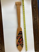 Full view of the front side of the paddle with a measuring tape beside it showing approximately 26 inches in length.