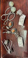 Four pairs of assorted sterling silver earrings displayed on wood surface showing detailed designs and stone colors