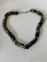 Full view of the vintage moss agate stone disk necklace laid flat showing all stone beads and clasp.