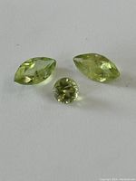 Photo showing all three vintage peridot gemstones, two marquise shaped and one round cut, light green color.
