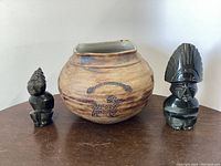 Photo showing the pottery jar centered with one obsidian figurine on each side, displaying the overall lot.