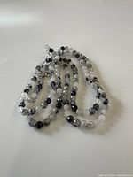 Necklace laid in coiled arrangement showing faceted rutilated quartz beads mixed with black beads and the sterling clasp.