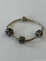 Full view of the sterling silver snake chain bracelet with three distinct beads spaced along it.