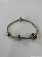 Full view of the sterling silver bracelet showing the snake chain design and three different silver beads including the clasp bead with visible engravings.