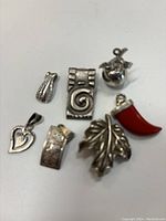 Clear photo showing all seven sterling silver pendants with different shapes and designs on a white background.